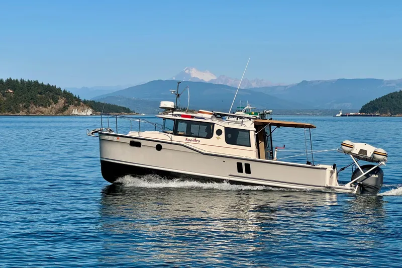 Slide: The Image of 2024 Ranger Tugs R-27 cruising on a scenic lake with mountainous backdrop. - 34