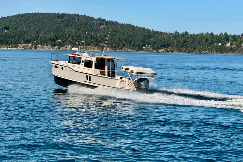 Slide: The Image of 2024 Ranger Tugs R-27 cruising on a scenic lake with forested hills. - 40