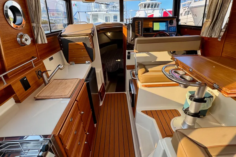 Slide: The Image of 2024 Ranger Tugs R-27 interior with wood finish, kitchenette, and seating area. - 5