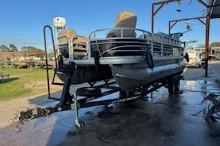 The Image of 2023 Sun Tracker Fishin' Barge 20 DLX pontoon boat on trailer, outdoor setting. - 1