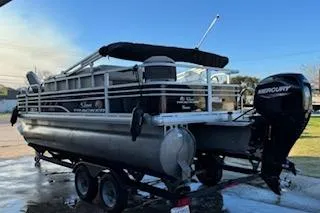 Slide: The Image of 2023 Sun Tracker Fishin' Barge 20 DLX pontoon boat on trailer, featuring a Mercury outboard motor. - 3
