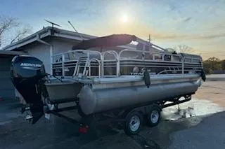 Slide: The Image of 2023 Sun Tracker Fishin' Barge 20 DLX pontoon boat on trailer at sunset. - 5