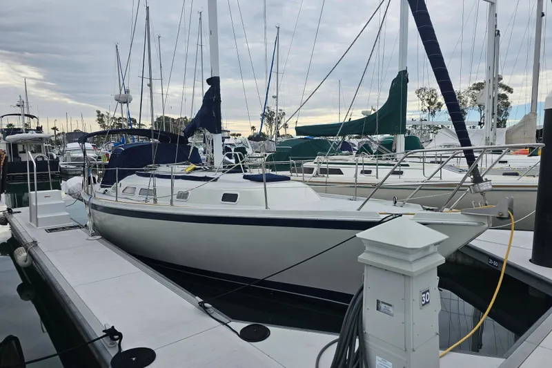 The Image of 1990 Ericson 34 sailboat docked at a marina under a cloudy sky. - 0