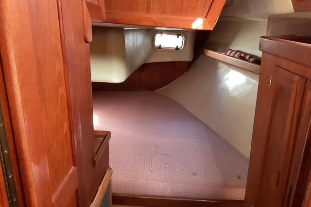 Slide: The Image of Interior cabin of a 1990 Ericson 34 sailboat with wooden finishes and a cozy berth. - 11