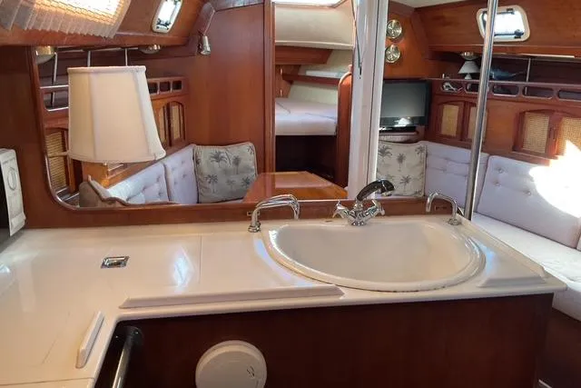 Slide: The Image of Interior of a 1990 Ericson 34 sailboat, featuring a cozy cabin with a sink and seating area. - 13