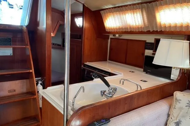 Slide: The Image of Interior of a 1990 Ericson 34 sailboat with wooden cabinetry and a compact kitchen area. - 17