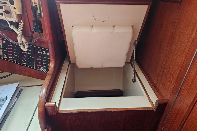 Slide: The Image of 1990 Ericson 34 yacht interior with open storage compartment and control panel. - 19