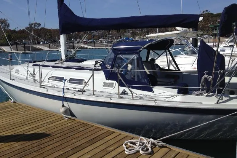 Slide: The Image of 1990 Ericson 34 sailboat docked at a marina with blue canvas covers. - 2