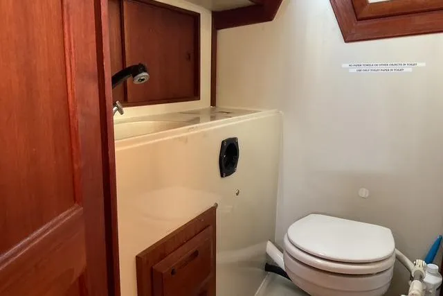 Slide: The Image of 1990 Ericson 34 yacht bathroom with wooden cabinets and compact toilet. - 21