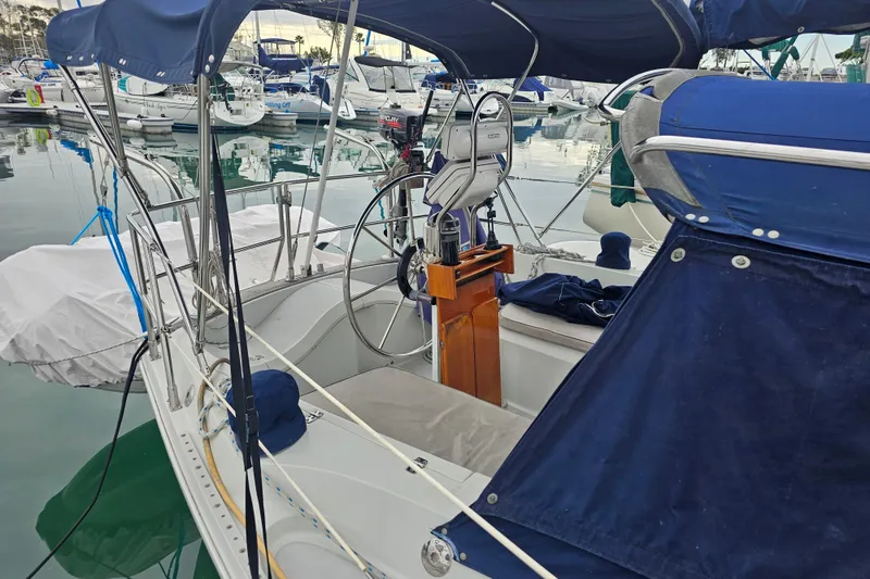 Slide: The Image of 1990 Ericson 34 sailboat cockpit with blue canopy, docked in marina. - 7