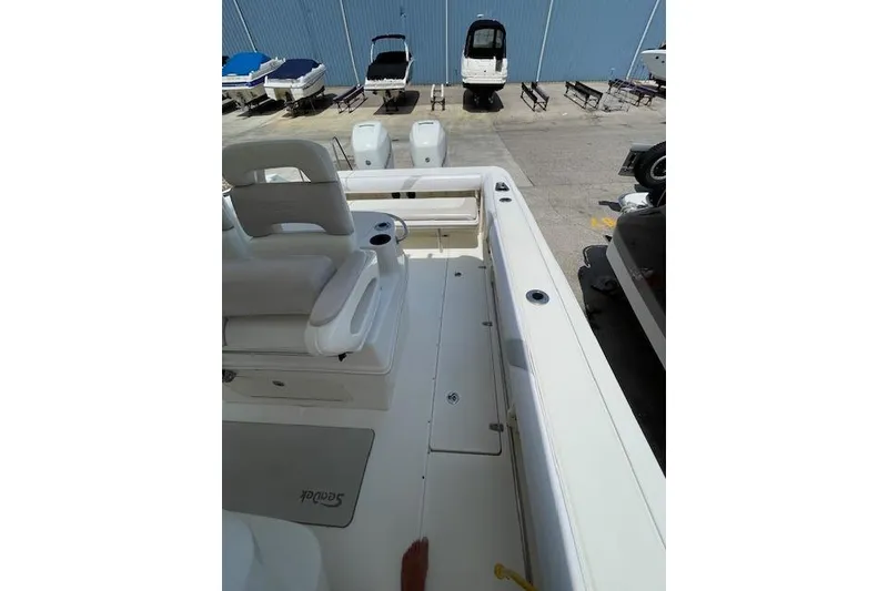 Slide: The Image of 2008 Boston Whaler 320 Outrage boat interior with seating and storage, docked near other boats. - 12