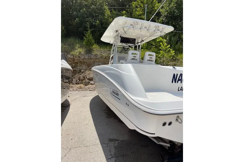 Slide: The Image of 2008 Boston Whaler 320 Outrage boat with white hull, parked outdoors. - 4