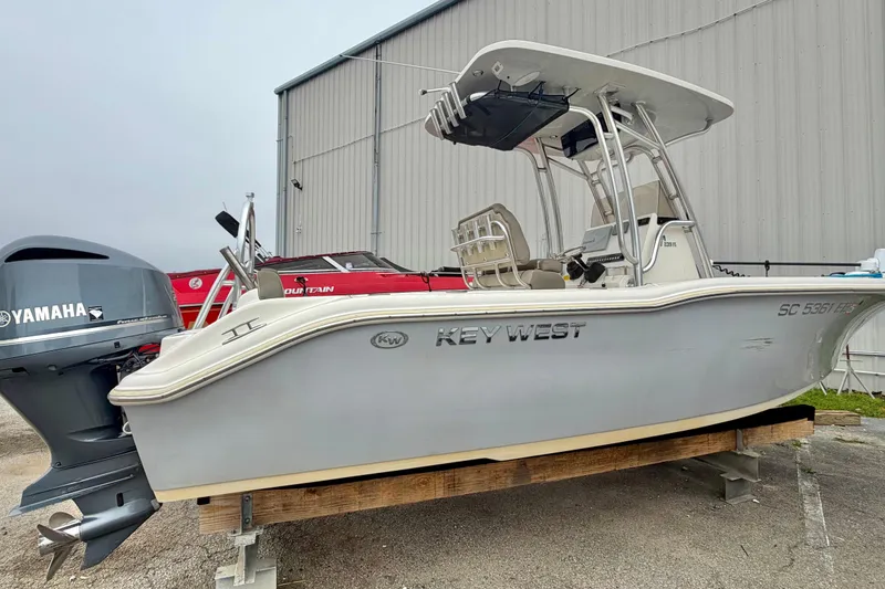 Slide: The Image of 2021 Key West 239 FS boat with Yamaha engine, displayed outdoors near a warehouse. - 12