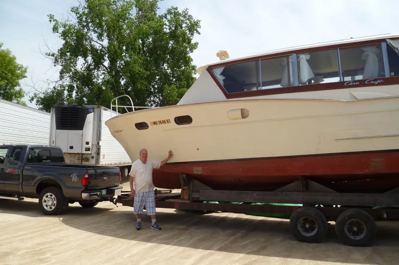 Slide: The Image of 1958 Chris-Craft 31 Sedan Cruiser on trailer with person and truck nearby. - 5
