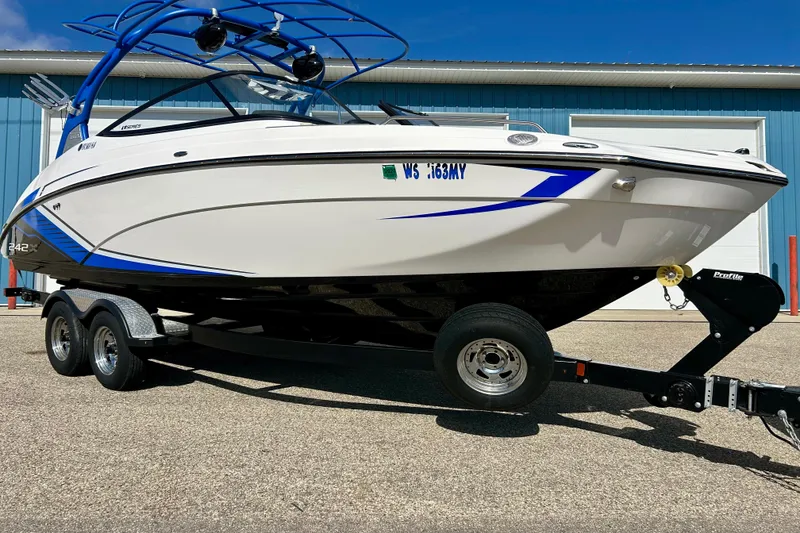 Slide: The Image of 2018 Yamaha Boats 242X on trailer, white and blue, parked outdoors. - 2
