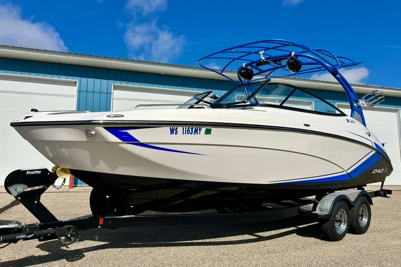Slide: The Image of 2018 Yamaha Boats 242X on trailer, white and blue design, parked outdoors. - 3
