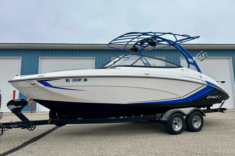 Slide: The Image of 2018 Yamaha Boats 242X on trailer, sleek design with blue accents, parked outdoors. - 58