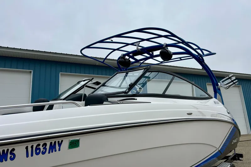 Slide: The Image of 2018 Yamaha Boats 242X with blue wakeboard tower, parked near blue building. - 63