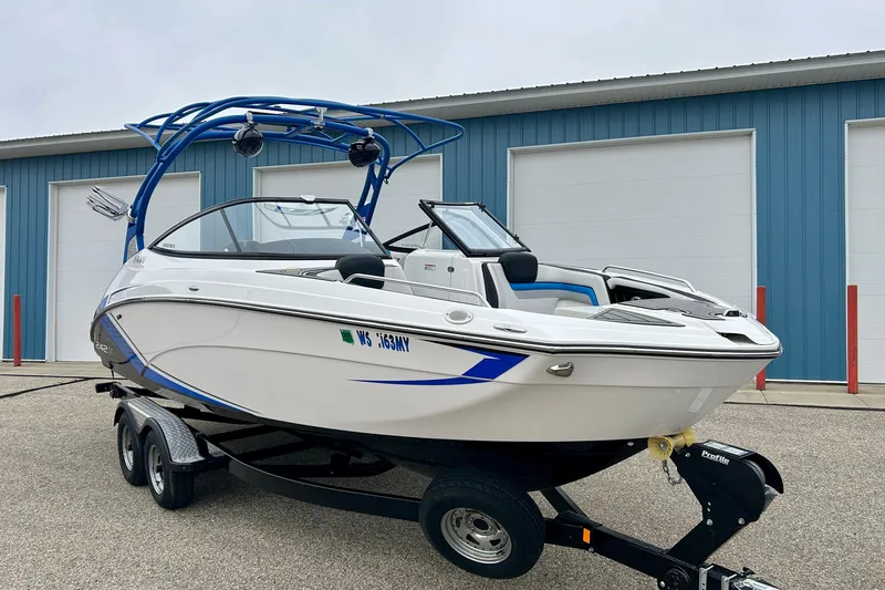 Slide: The Image of 2018 Yamaha Boats 242X on trailer, parked near blue building. - 80