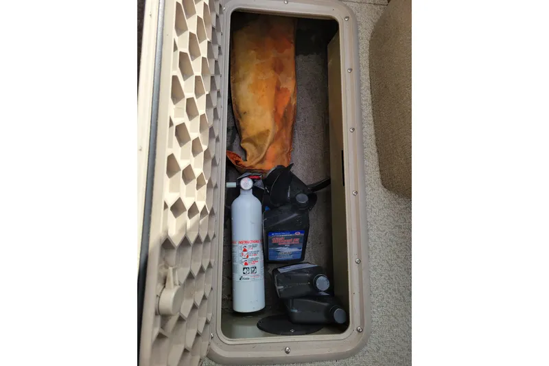 Slide: The Image of Storage compartment in a 2005 Lowe Fish & Ski 165 boat with fire extinguisher and supplies. - 24