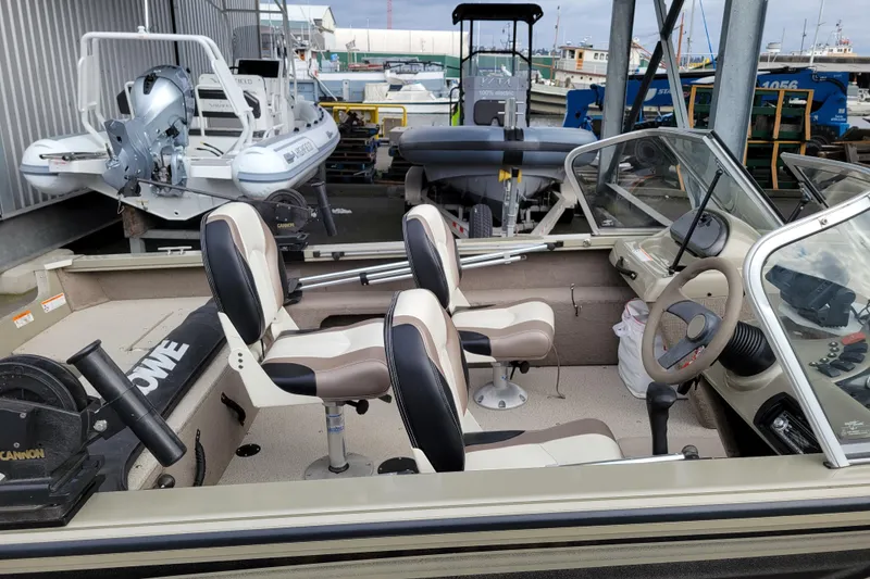 Slide: The Image of 2005 Lowe Fish & Ski 165 boat interior with seating and steering wheel, docked at marina. - 8