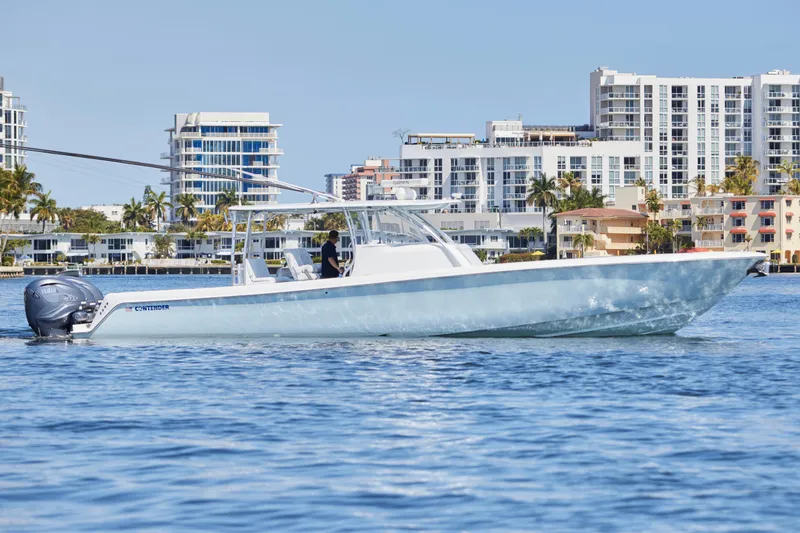 Slide: The Image of 2022 Contender 44 Fisharound boat cruising near modern waterfront buildings. - 2