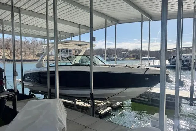 Slide: The Image of 2021 Chaparral 307 SSX boat docked under a covered marina on a sunny day. - 1