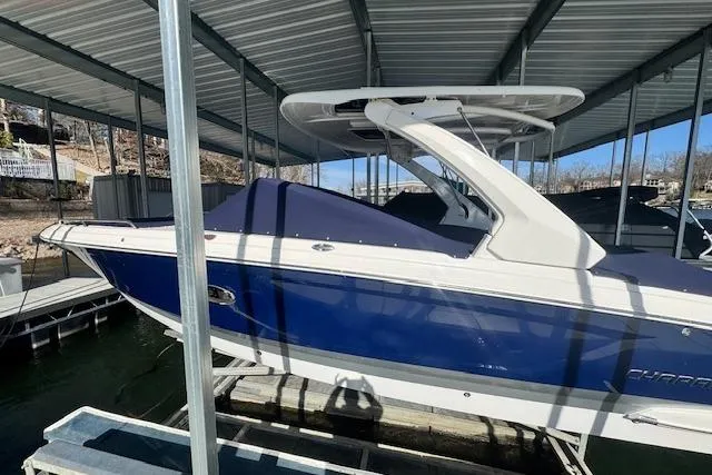 Slide: The Image of 2021 Chaparral 307 SSX boat in dock, blue and white exterior, covered, under metal roof. - 36