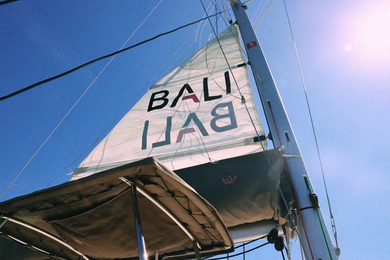 Slide: The Image of Sailing catamaran Bali CATSPACE 2023 with sunlit sails against a clear blue sky. - 14