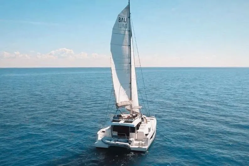 Slide: The Image of 2023 Bali CATSPACE sailing on open ocean under clear blue sky. - 2