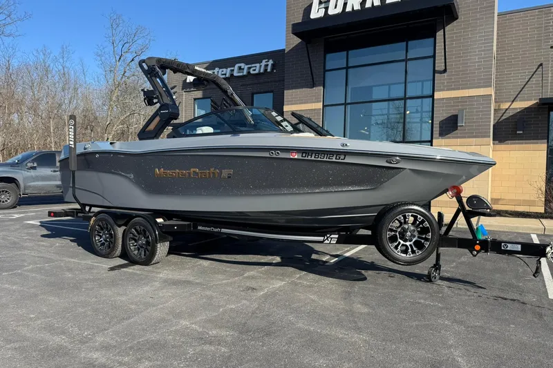 The Image of 2023 MasterCraft XT23 boat on trailer outside dealership. - 1