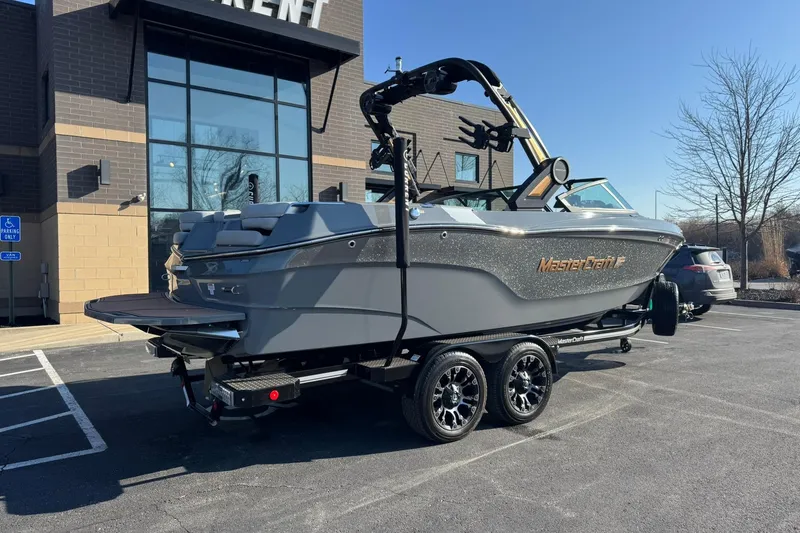 Slide: The Image of 2023 MasterCraft XT23 boat on trailer in parking lot, near modern building. - 3