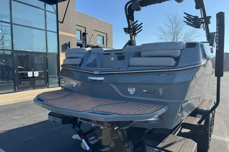 Slide: The Image of 2023 MasterCraft XT23 boat on trailer, parked outside a modern building. - 4