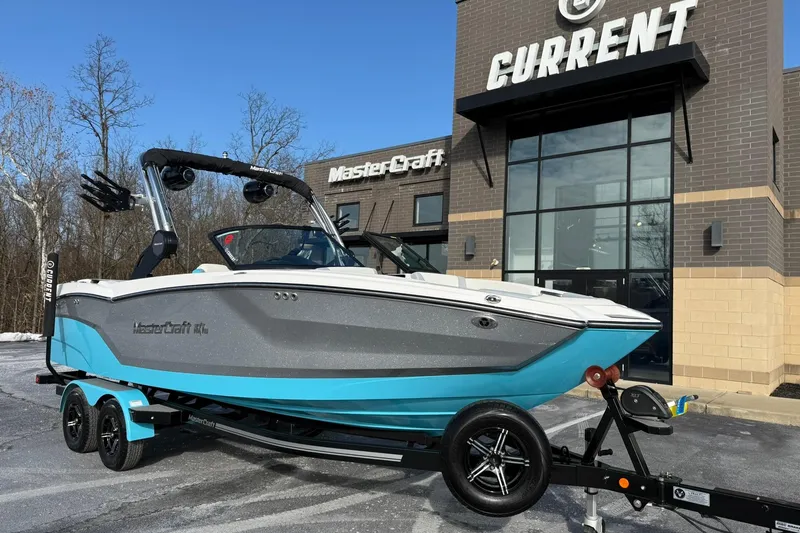 The Image of 2023 MasterCraft NXT23 boat on trailer outside dealership, showcasing sleek design. - 0