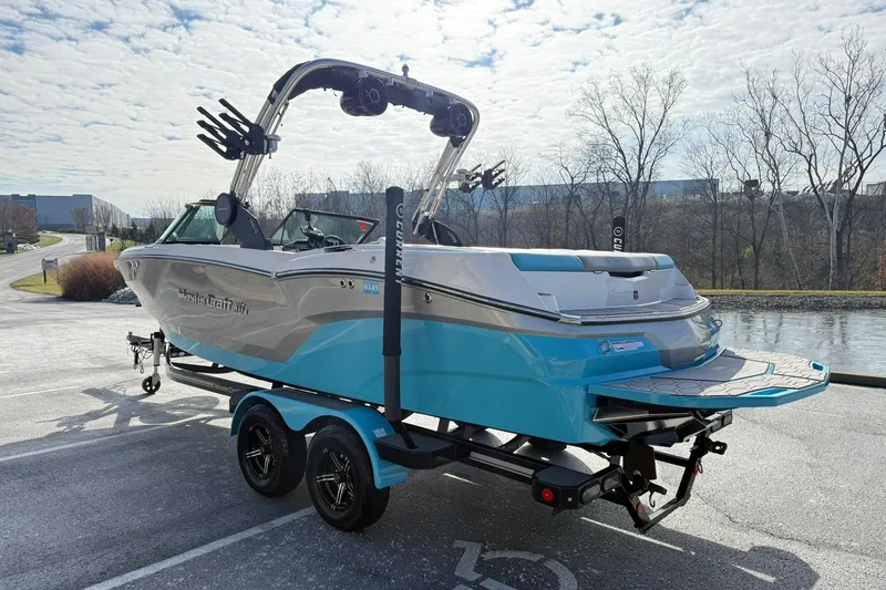 Slide: The Image of 2023 MasterCraft NXT23 boat on trailer, parked near a scenic waterway. - 12