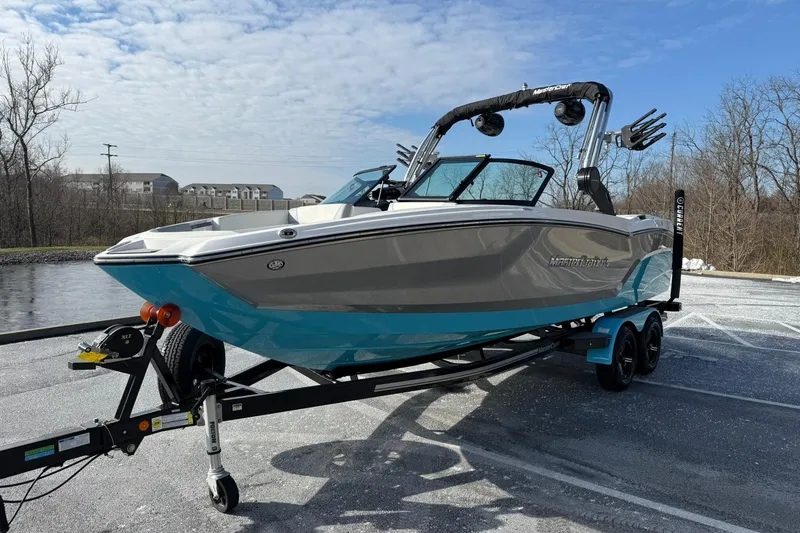 Slide: The Image of 2023 MasterCraft NXT23 boat on trailer in parking lot, clear sky background. - 13
