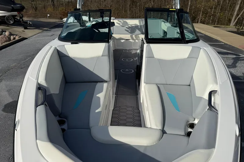 Slide: The Image of 2023 MasterCraft NXT23 boat interior with gray and white seating, cup holders, and windshield. - 15