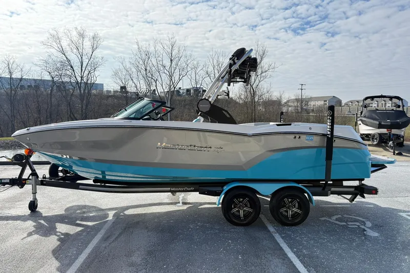 Slide: The Image of 2023 MasterCraft NXT23 boat on trailer, blue and gray design, parked outdoors. - 4