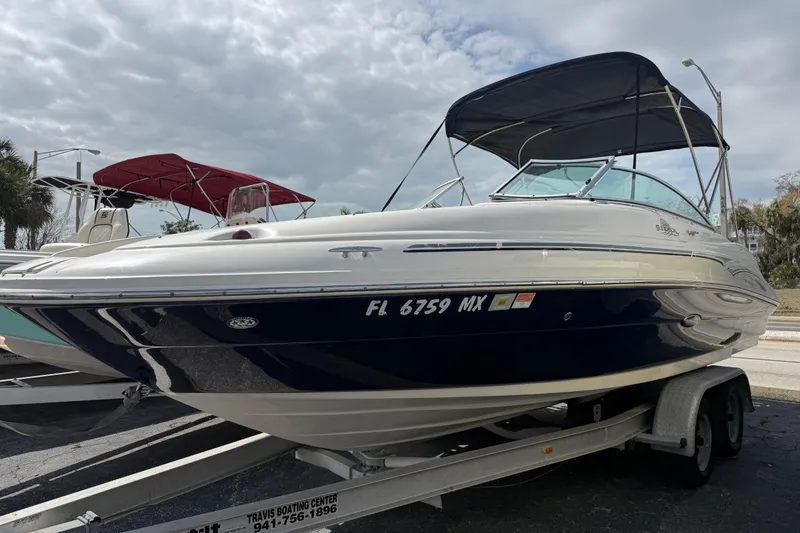 The Image of 2005 Sea Ray 220 Sundeck boat on trailer, featuring a sleek design and canopy. - 0