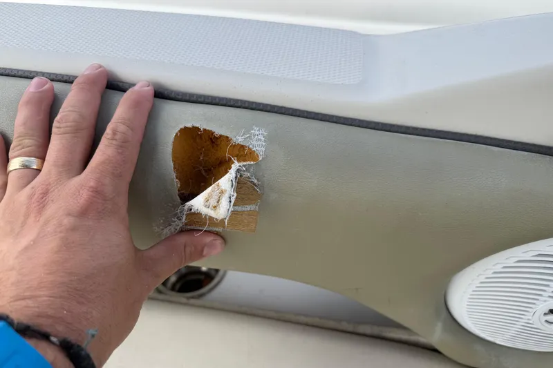 Slide: The Image of Hand inspecting damage on 2005 Sea Ray 220 Sundeck boat interior panel. - 11