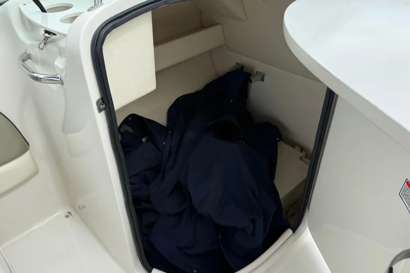 Slide: The Image of 2005 Sea Ray 220 Sundeck storage compartment with dark fabric inside. - 17
