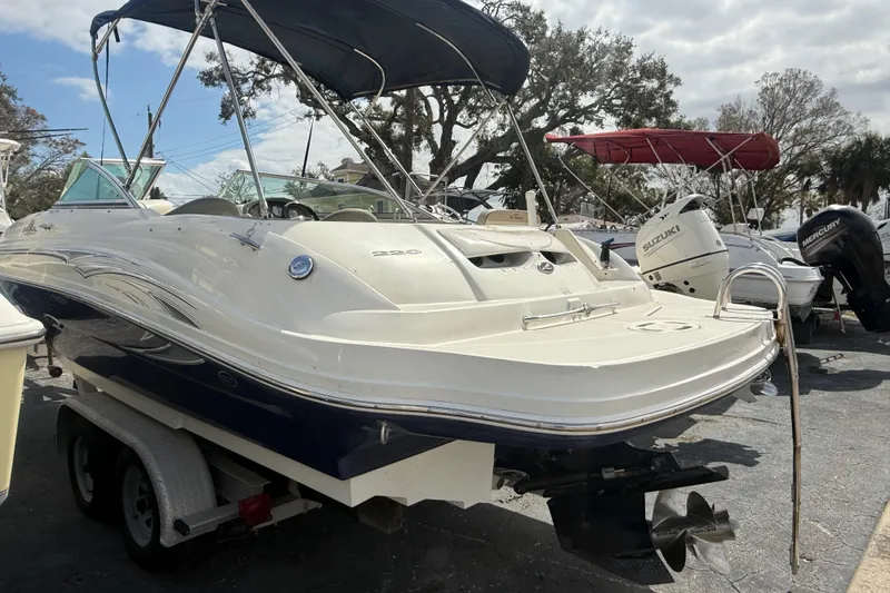 Slide: The Image of 2005 Sea Ray 220 Sundeck boat with canopy on trailer, parked outdoors. - 2