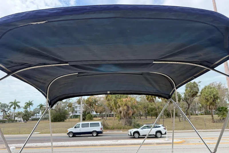 Slide: The Image of Bimini top of 2005 Sea Ray 220 Sundeck with road and trees in background. - 31