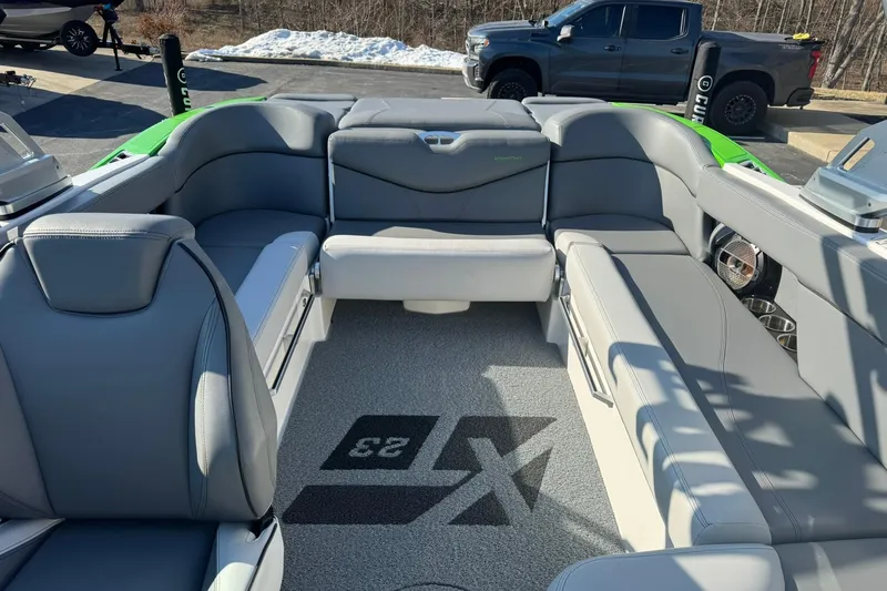 Slide: The Image of 2019 MasterCraft XT23 boat interior with gray seating and logo on carpet. - 12