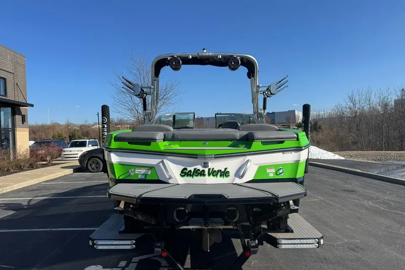 Slide: The Image of 2019 MasterCraft XT23 boat in green and white, parked outdoors on a sunny day. - 5