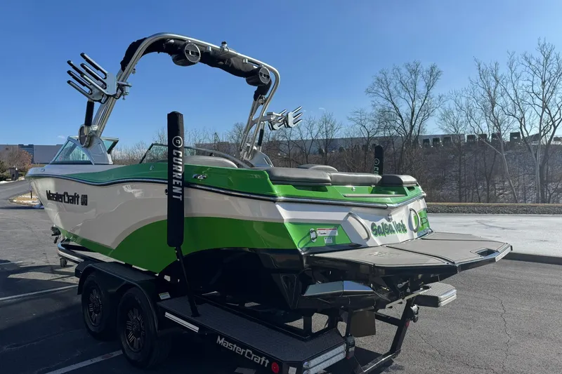 Slide: The Image of 2019 MasterCraft XT23 boat on trailer, green and white design, parked outdoors. - 6