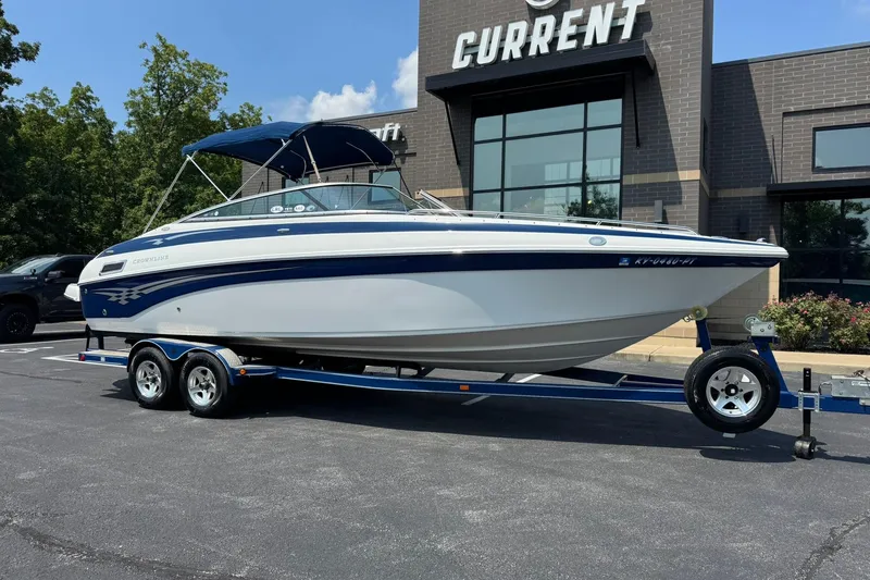 The Image of 2005 Crownline 270 BR boat on trailer, parked outside a building, under clear skies. - 1
