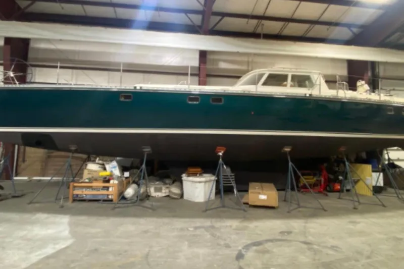 The Image of 1996 Blue Water 60 Ketch sailboat in dry dock, supported by stands in a warehouse. - 1