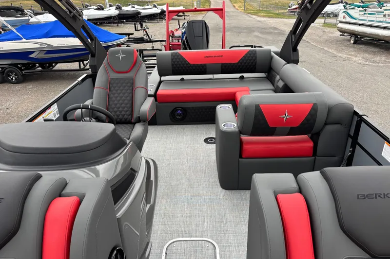Slide: The Image of 2026 Berkshire 25SB2 STS pontoon boat interior with red and black seating, cup holders, and steering console. - 17