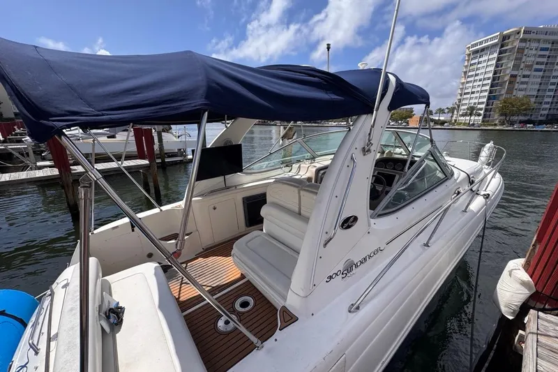 Slide: The Image of 2005 Sea Ray 300 Sundancer boat docked, featuring a blue canopy and spacious deck. - 11